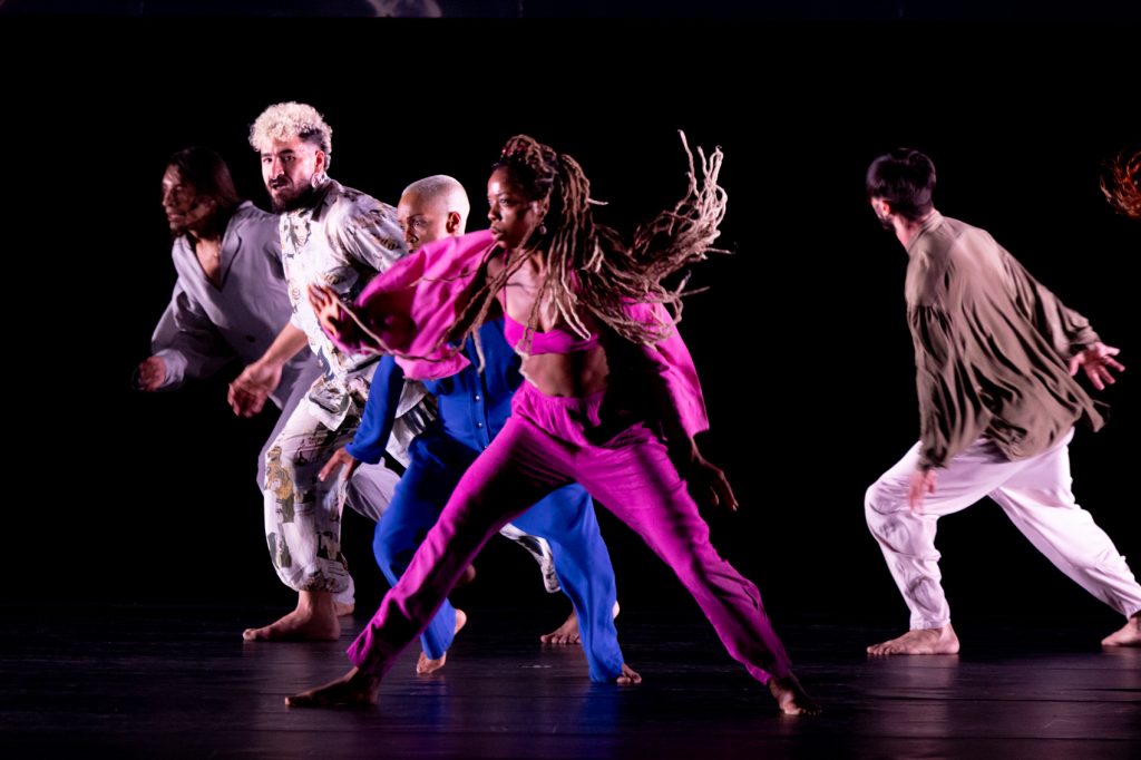 Foto com quatro bailarinos dançando juntos.