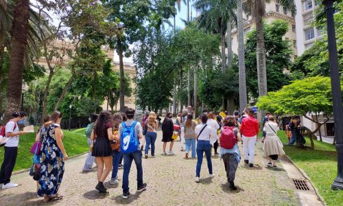 Grupo de pessoas participam de atividade cultural em área externa com árvores e gramado